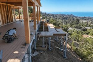 Multi-level hillside deck under construction on a sloped Montecito lot with engineered footings and structural steel supports